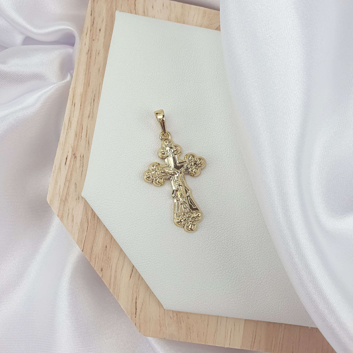 Paauksuotas kryžius su nukryžiuotojo reljefu ir gėlės formos galais ant medinės lentelės