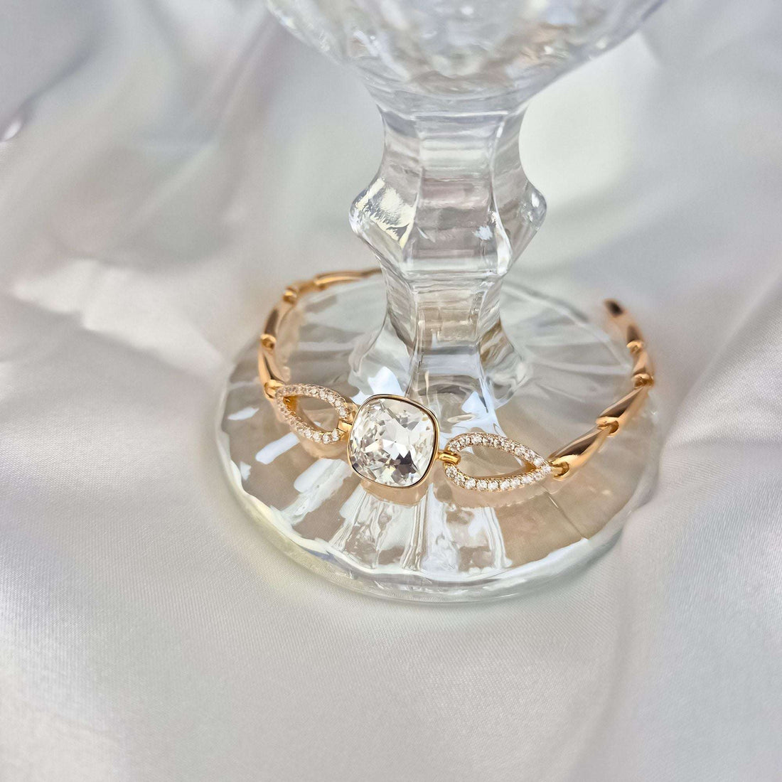 Apyrankė su žėrinčiu Swarovski kristalu ant stiklo padėklo, matyti cirkoniais puoštos grandys