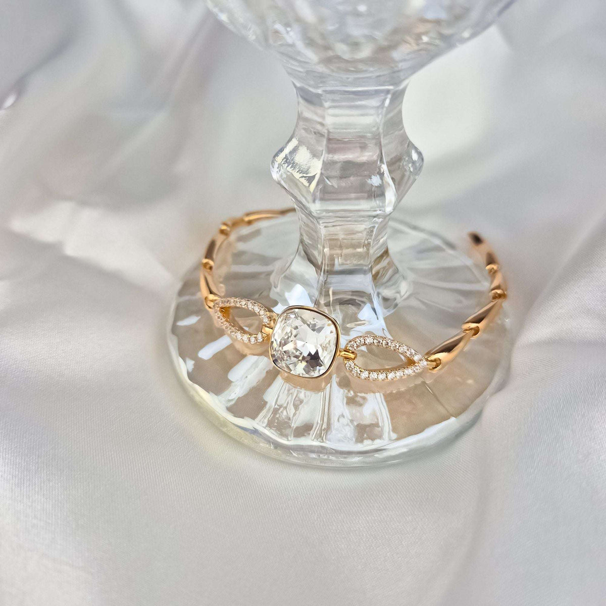 Apyrankė su žėrinčiu Swarovski kristalu ant stiklo padėklo, matyti cirkoniais puoštos grandys